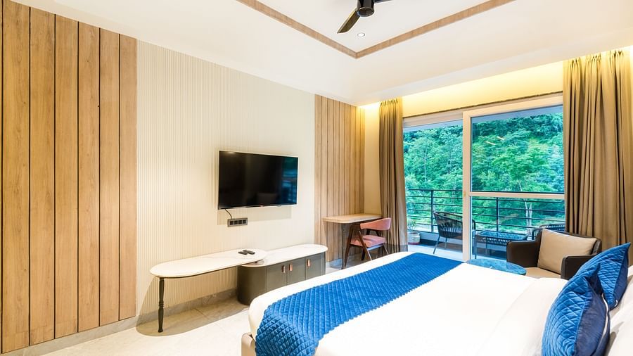 Deluxe Room at DLS Divine River Resort and Spa featuring a bed, TV and a balcony with forest views  